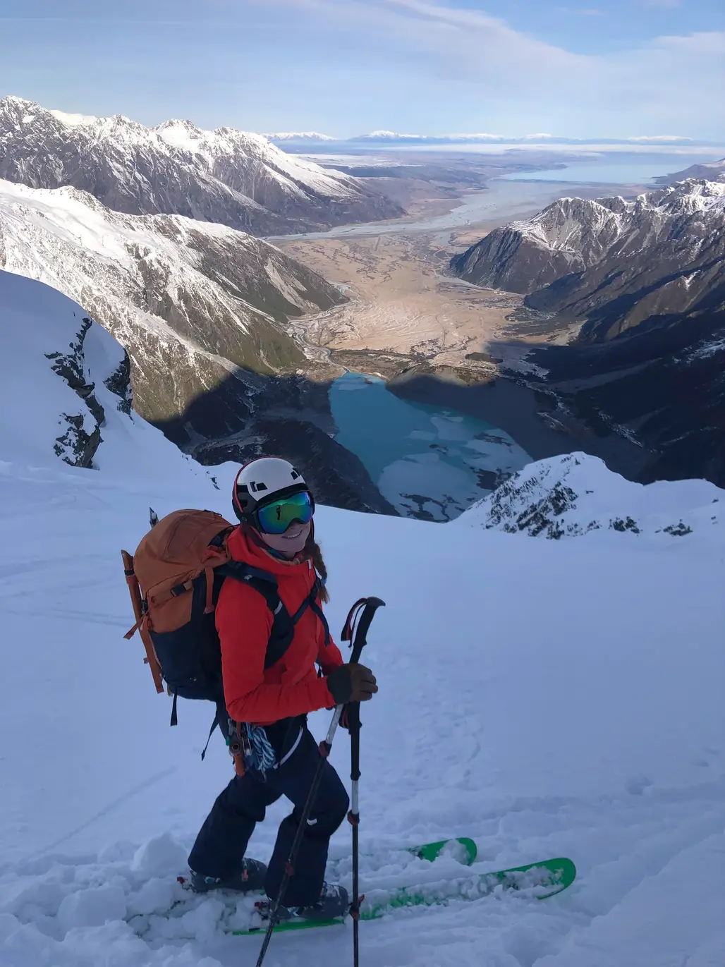 Petrouchka smiling on a ski descent above a long alpine valley